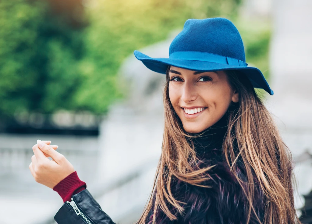 Younger female smiling wearing a blue hat