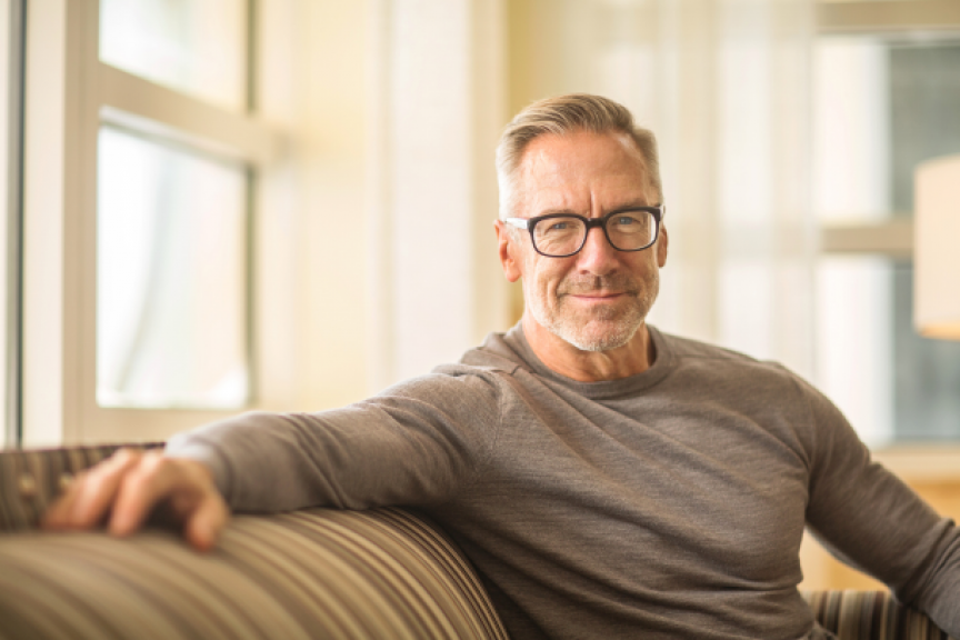 smiling man in glasses sitting on a couch