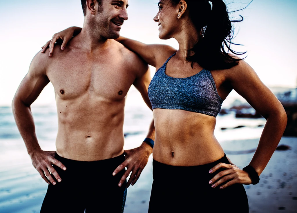 Physically fit couple looking at each other on a beach