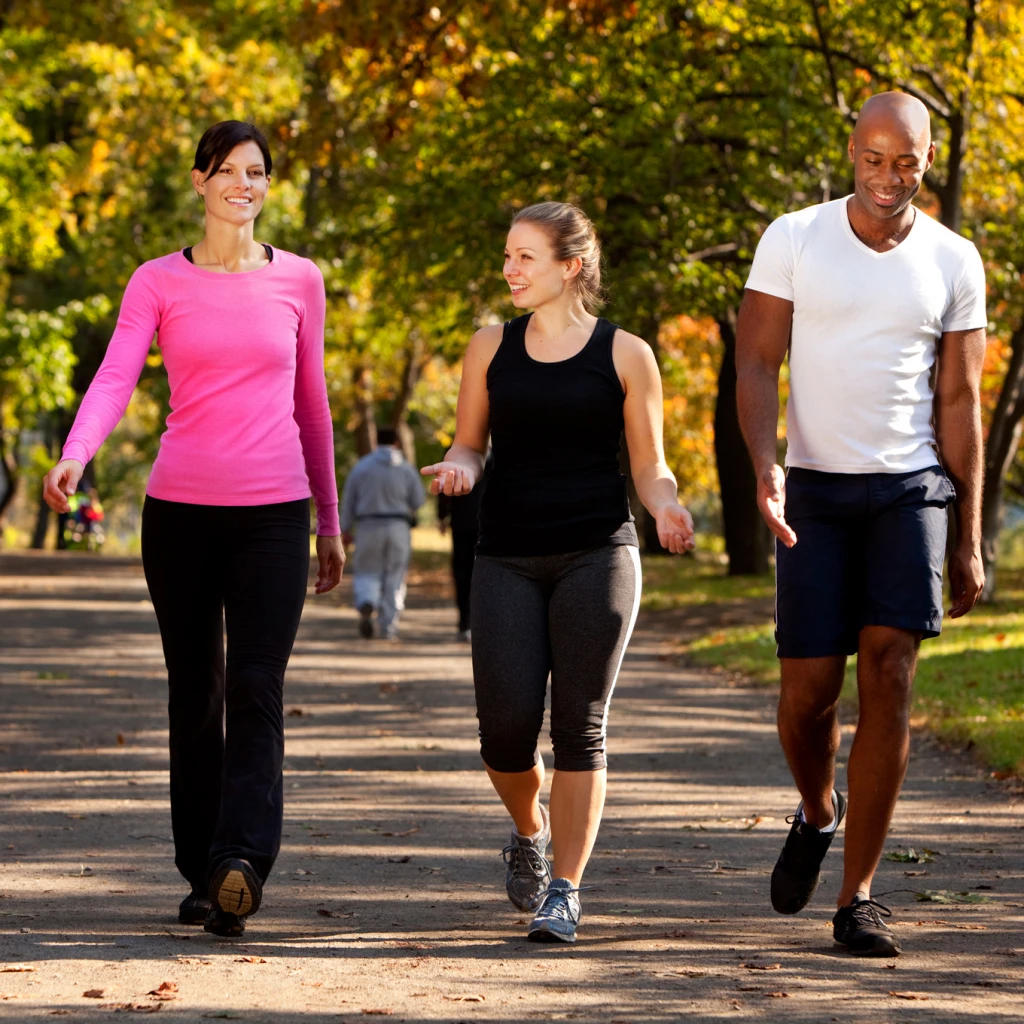Group of 3 adults wearing exercise clothes, outside walking